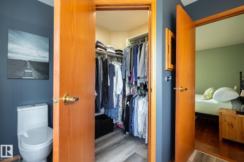 Walk-in closet in the primary bedroom suite featuring wire shelving and wood-finish flooring - 114 Reichert Drive, Beaumont, AB 