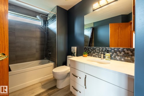 Bathroom featuring a white vanity with an integrated sink, hexagon tile backsplash, and a large mirror - 114 Reichert Drive, Beaumont, AB 