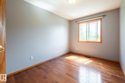 Bedroom featuring wood-finish flooring, a window with wood trim, and light gray walls - 