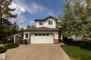 Two-story residence featuring white siding, a two-car garage with paneling, and a concrete driveway - 114 Reichert Drive, Beaumont, AB 