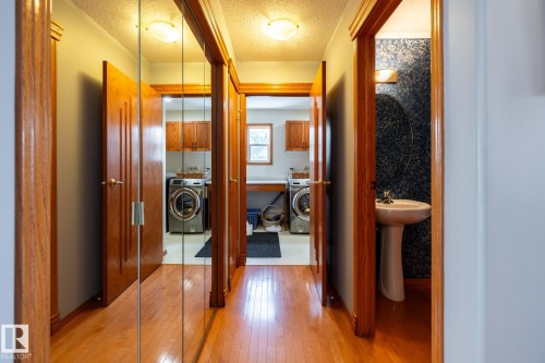 Hallway with wood-finish flooring, mirrored closet doors, leading to the garage and laundry area - 114 Reichert Drive, Beaumont, AB 