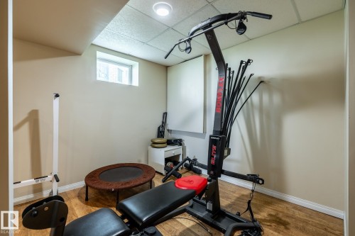 Versatile bonus room featuring wood-finish flooring, neutral wall paint, a drop ceiling, recessed lighting, and a high-set window - 114 Reichert Drive, Beaumont, AB 