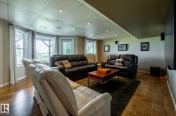 Spacious lower-level area with a door into the back yard, featuring recessed lighting, wood-finish flooring, and multiple windows - 