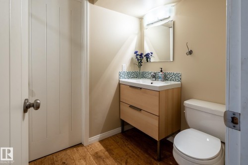 Basement bathroom featuring a floating wood-finish vanity with an integrated sink, mosaic tile backsplash, and a wall-mounted mirror - 114 Reichert Drive, Beaumont, AB 