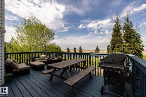 Expansive outdoor deck overlooking the 14th green at Coloniale Golf Course featuring blue-painted wood flooring and dark balusters - 114 Reichert Drive, Beaumont, AB 