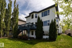 Rear exterior featuring white horizontal siding, a multi-level deck, a walk-out lower level, and mature landscaping - 