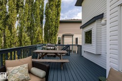 Spacious outdoor deck featuring a dark blue wood-finish surface, coordinating railings, and tall mature trees providing natural screening - 