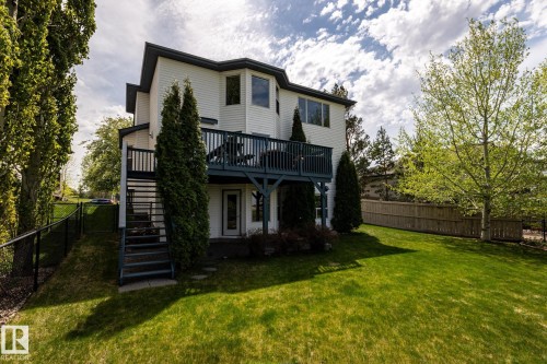 Two-story residence with walkout basement, a white exterior and dark trim, featuring an upper-level deck - 114 Reichert Drive, Beaumont, AB 