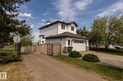 Two-story residence featuring white siding, a contrasting dark roof, and an attached garage with a white sectional door, showing the cart path on the west side of the home - 