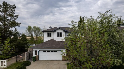 Residence featuring white siding, dark shingle roofing, and an oversized double garage - 114 Reichert Drive, Beaumont, AB 