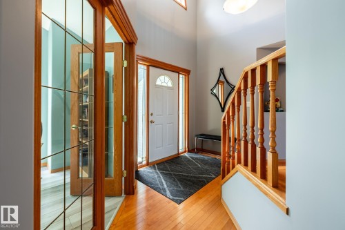 Inviting grand entry featuring wood flooring and a wooden staircase with balusters - 114 Reichert Drive, Beaumont, AB 