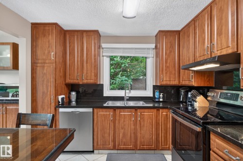 Kitchen featuring wood-finish cabinetry, dark countertops, and tile flooring - 31 Alpine Boulevard, St. Albert, AB 