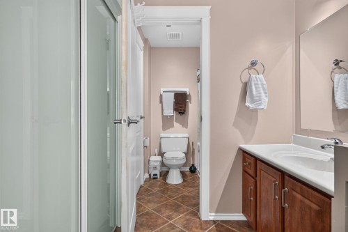 Bathroom featuring a glass-enclosed shower, a vanity with a white countertop and wood-finish cabinetry, and a toilet - 31 Alpine Boulevard, St. Albert, AB 