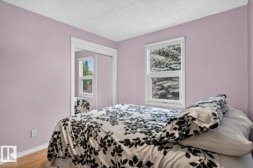 Room with two windows, wood-finish flooring, light-colored walls, white trim, and a mirrored sliding closet door - 31 Alpine Boulevard, St. Albert, AB 