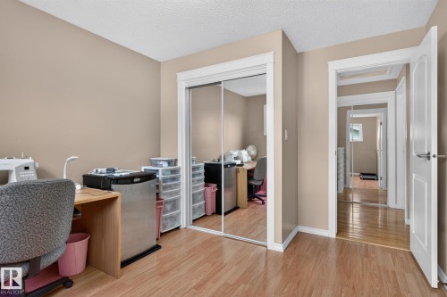 Room featuring wood-finish flooring, neutral wall paint, white trim, and a mirrored closet - 31 Alpine Boulevard, St. Albert, AB 