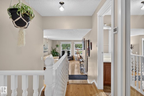 Upper-level hallway featuring a white baluster railing and wood-finish flooring - 31 Alpine Boulevard, St. Albert, AB 
