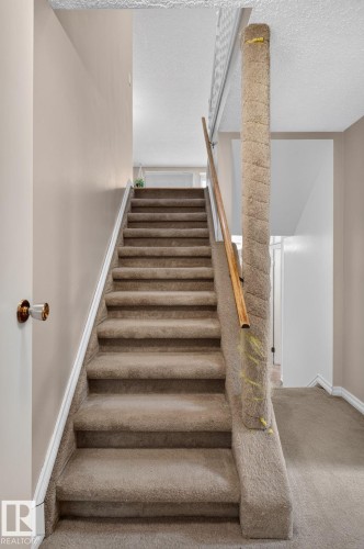 Staircase with carpeted treads and risers, featuring a wooden handrail and a carpet-wrapped newel post - 31 Alpine Boulevard, St. Albert, AB 