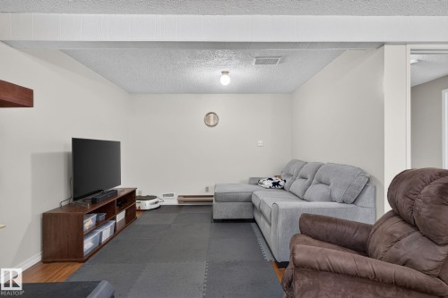 Finished lower level space featuring a drop ceiling, light-toned walls, and a combination of wood-finish flooring and black mat flooring - 31 Alpine Boulevard, St. Albert, AB 