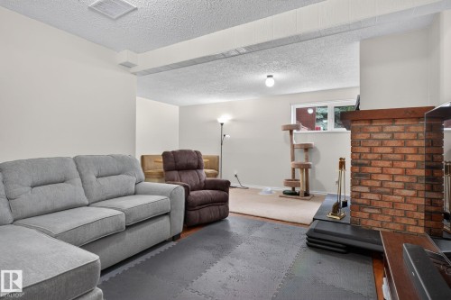 Brick fireplace with wood mantle and hearth, recessed window, and light-colored carpeting - 31 Alpine Boulevard, St. Albert, AB 