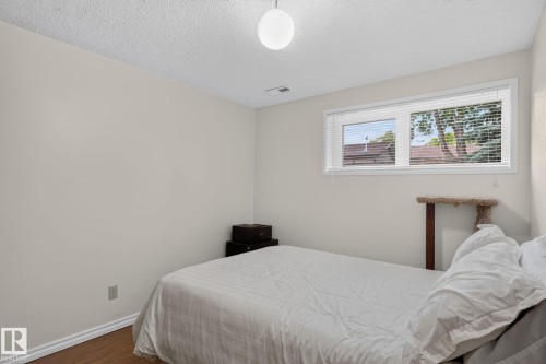 Bedroom featuring light-toned walls, wood-finish flooring, and white baseboards - 31 Alpine Boulevard, St. Albert, AB 