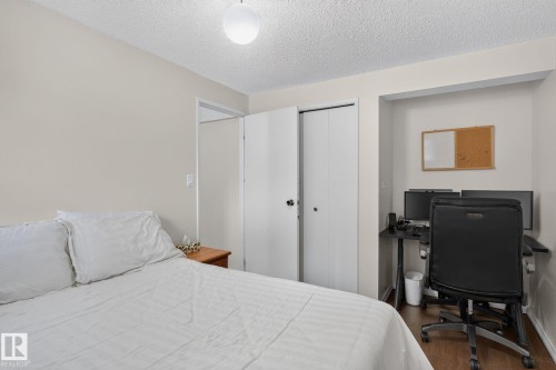 Bedroom featuring neutral wall paint, wood-finish flooring, a built-in closet with bi-fold doors, a recessed desk area, and a ceiling-mounted globe light fixture - 31 Alpine Boulevard, St. Albert, AB 