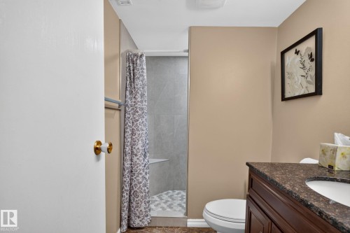 Bathroom featuring a walk-in shower with glass enclosure, hexagonal floor tiling, and a built-in shower bench - 31 Alpine Boulevard, St. Albert, AB 