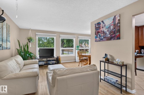 Open concept living area featuring wood-finish flooring, neutral wall tones, and multiple windows - 31 Alpine Boulevard, St. Albert, AB 