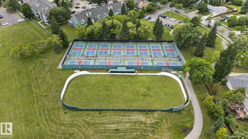 Recreational outdoor area featuring multiple hard courts with green and blue surfaces, a fenced green space, and surrounding green areas - 31 Alpine Boulevard, St. Albert, AB 
