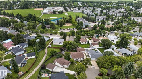 Residential area featuring a mix of single-family homes and multi-story buildings, abundant mature trees, paved streets, and a public park with recreational fields and a tennis court - 31 Alpine Boulevard, St. Albert, AB 