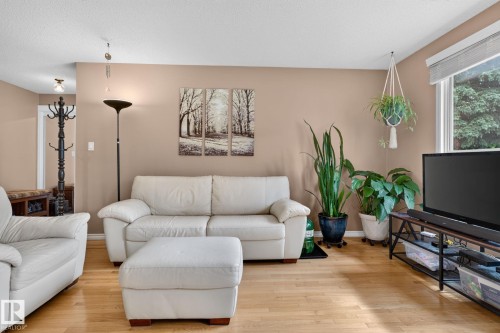 Hardwood-finish flooring throughout, featuring a neutral wall color palette, a large window providing ample natural light, and recessed lighting in the ceiling - 31 Alpine Boulevard, St. Albert, AB 
