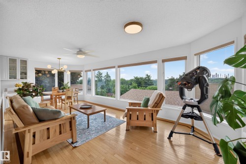 Open-concept living area featuring numerous large windows, wood-finish flooring, and white walls - 3411 103 Avenue, Edmonton, AB 