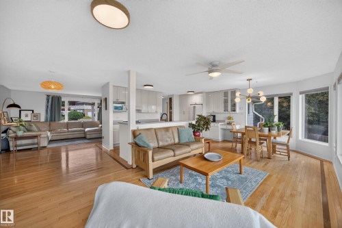 Hardwood flooring throughout a spacious living area, featuring a modern ceiling fan, recessed lighting, and large windows - 3411 103 Avenue, Edmonton, AB 