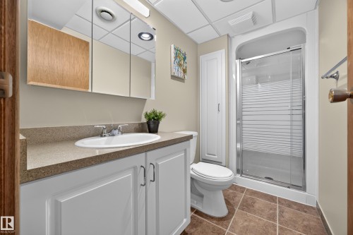 Bathroom featuring a white vanity with recessed panel doors, a durable countertop, and a glass-enclosed shower - 3411 103 Avenue, Edmonton, AB 