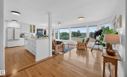 Hardwood flooring extends throughout this space featuring a kitchen with white cabinetry, a center island with sink, and a full suite of appliances - 3411 103 Avenue, Edmonton, AB 