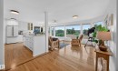 Hardwood flooring extends throughout this space featuring a kitchen with white cabinetry, a center island with sink, and a full suite of appliances - 3411 103 Avenue, Edmonton, AB 