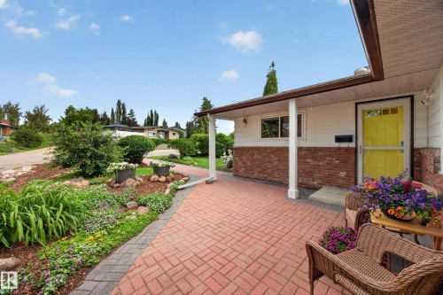 Brick paver walkway leading to a covered entry with a vibrant yellow door - 3411 103 Avenue, Edmonton, AB 