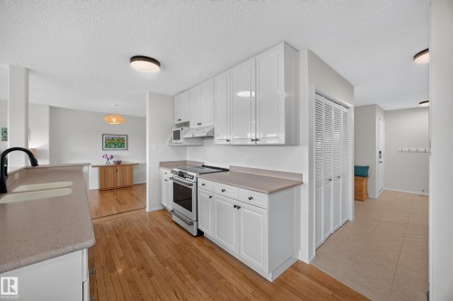 Kitchen featuring white cabinetry, light-toned countertops, a stainless steel electric range, and wood-finish flooring - 3411 103 Avenue, Edmonton, AB 