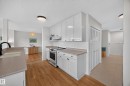 Kitchen featuring white cabinetry, light-toned countertops, a stainless steel electric range, and wood-finish flooring - 3411 103 Avenue, Edmonton, AB 