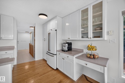 Kitchen with white cabinetry, light-toned countertops, and wood-finish flooring - 3411 103 Avenue, Edmonton, AB 