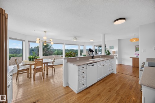Open-concept kitchen featuring white cabinetry, light-toned countertops, and a built-in dishwasher - 3411 103 Avenue, Edmonton, AB 
