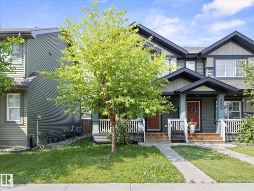 Contemporary townhome exterior featuring multi-toned siding, gabled rooflines, white railing accents, and a sidewalk entrance - 473 Orchards Boulevard, Edmonton, AB 