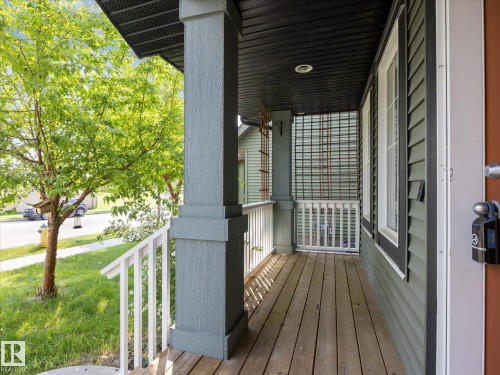 Inviting front porch featuring wood-finish flooring, white railings, and a prominent support column - 473 Orchards Boulevard, Edmonton, AB 