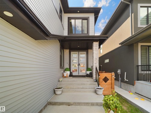 Modern exterior featuring light gray horizontal siding, an elevated entryway, and a covered porch - 320 38 Street, Edmonton, AB 