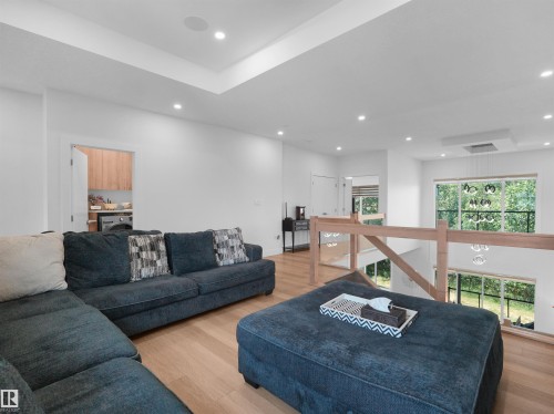 Open-concept bonus space featuring wood-finish flooring, recessed lighting, and a tray ceiling - 320 38 Street, Edmonton, AB 