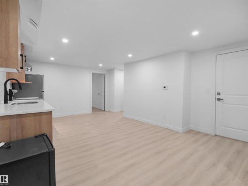 Bright, open-concept living space featuring light wood-finish flooring, recessed lighting, and crisp white walls - 320 38 Street, Edmonton, AB 