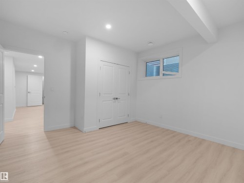 Spacious room featuring light wood-finish flooring, recessed lighting, and a double-door closet - 320 38 Street, Edmonton, AB 