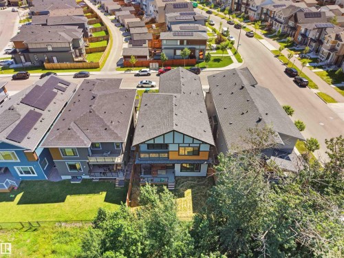 Modern multi-story property with a dark grey shingle roof, solar panel installation, and a contemporary facade featuring light wood-look and dark grey siding - 320 38 Street, Edmonton, AB 