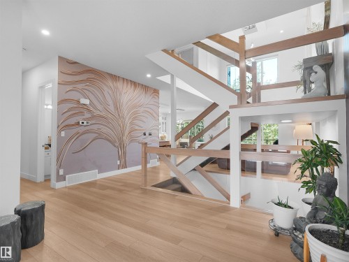 Open-concept entry foyer featuring wood-finish flooring and a striking wall mural - 320 38 Street, Edmonton, AB 