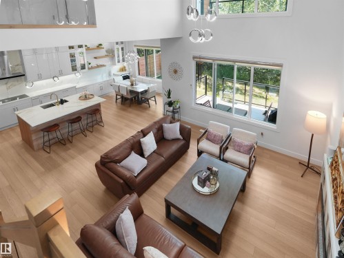 Open-concept living space featuring wood-finish flooring throughout, a modern kitchen with a large island and light-toned cabinetry, and a dining area with built-in seating - 320 38 Street, Edmonton, AB 