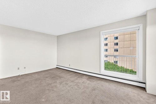 Expansive room featuring plush wall-to-wall carpeting and neutral wall tones - 806 10545 Saskatchewan Drive, Edmonton, AB 